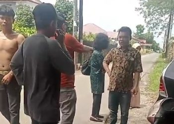 Warga meminta Ardion Sitompul, Pengacara Frida Mona Simarmata untuk meninggalkan lokasi tanah. Sedangkan Frida Mona Simarmata (pakai baju hijau) disamping pengacaranya tak mau menampilkan wajahnya saat diabadikan warga.